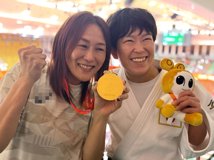 金メダルで喜ぶ様子の写真。左に磯崎コーチ、右に半谷選手が映っている。