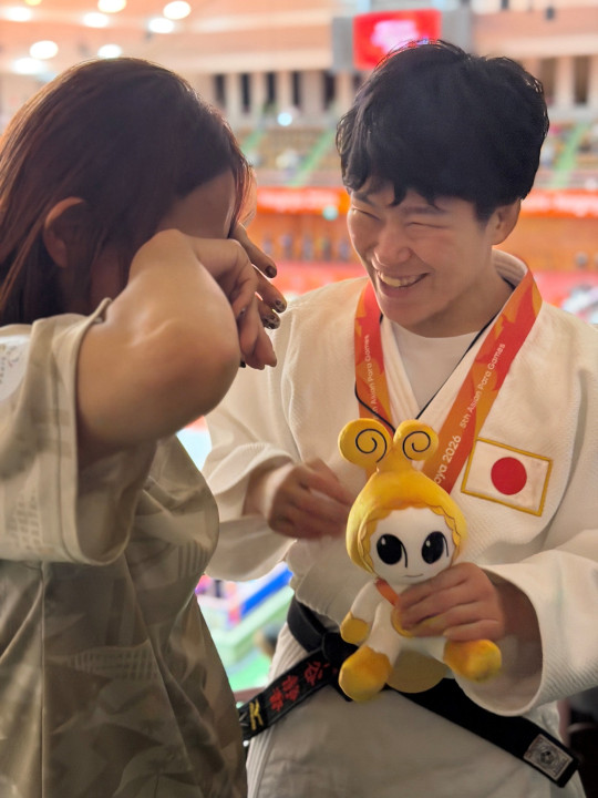 金メダルで喜ぶ様子の写真。左に磯崎コーチ、右に半谷選手が映っている。